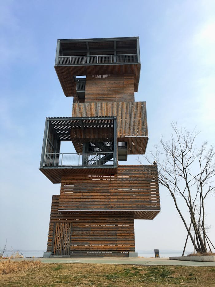 Unique modern wooden tower featuring geometric design and minimalist lines under a blue sky.